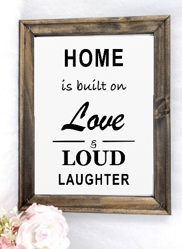 Home Is Built on Love and Loud Laughter framed canvas sign styled with soft pink flowers