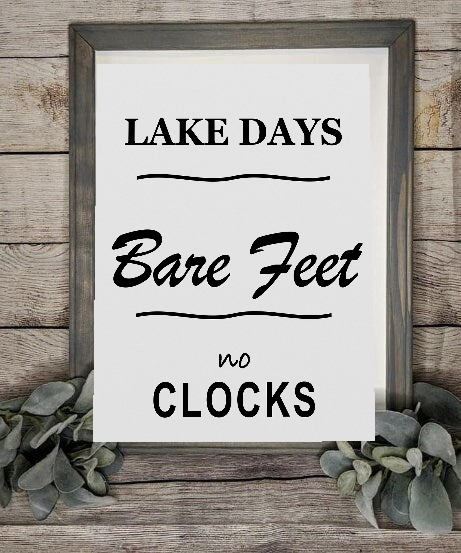Lake Days Bare Feet No Clocks framed canvas sign styled with greenery on a rustic wood wall
