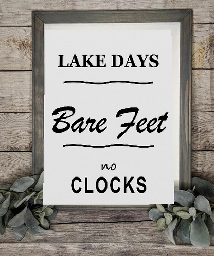 Lake Days Bare Feet No Clocks framed canvas sign styled with greenery on a rustic wood wall
