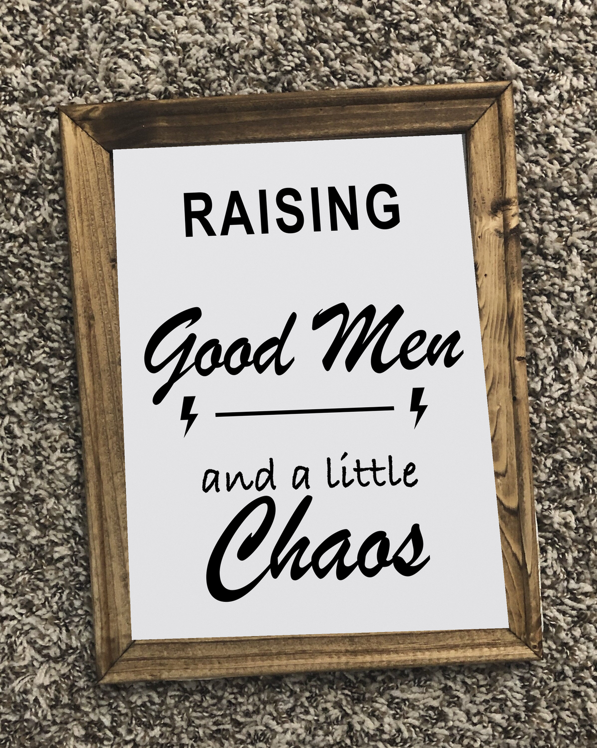 Raising Good Men and a Little Chaos framed canvas sign photographed on a textured carpet